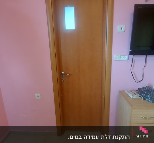 דלת עץ עם חלון קטן וידית מתכת